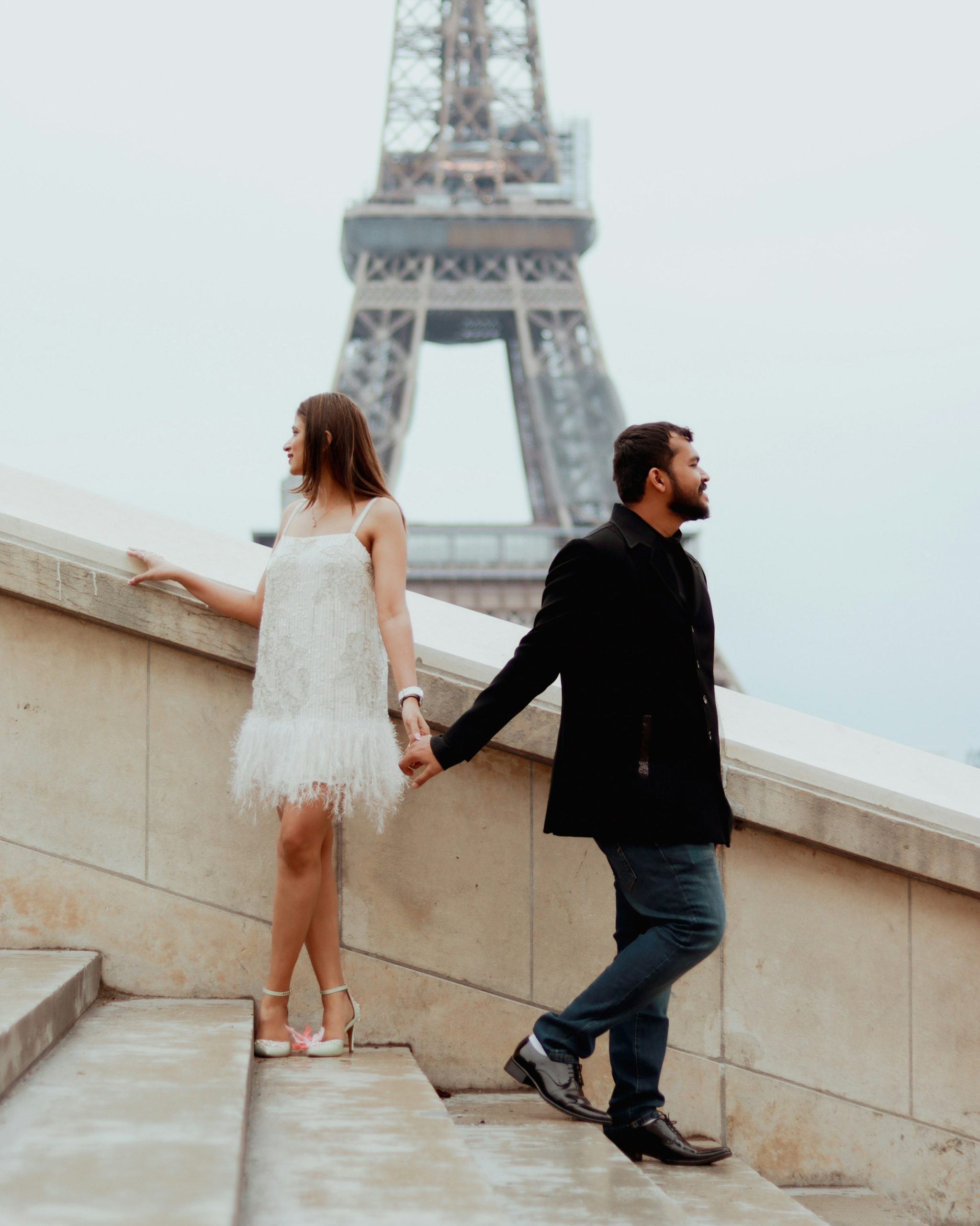 Un couple se tient la main près de la tour Eiffel