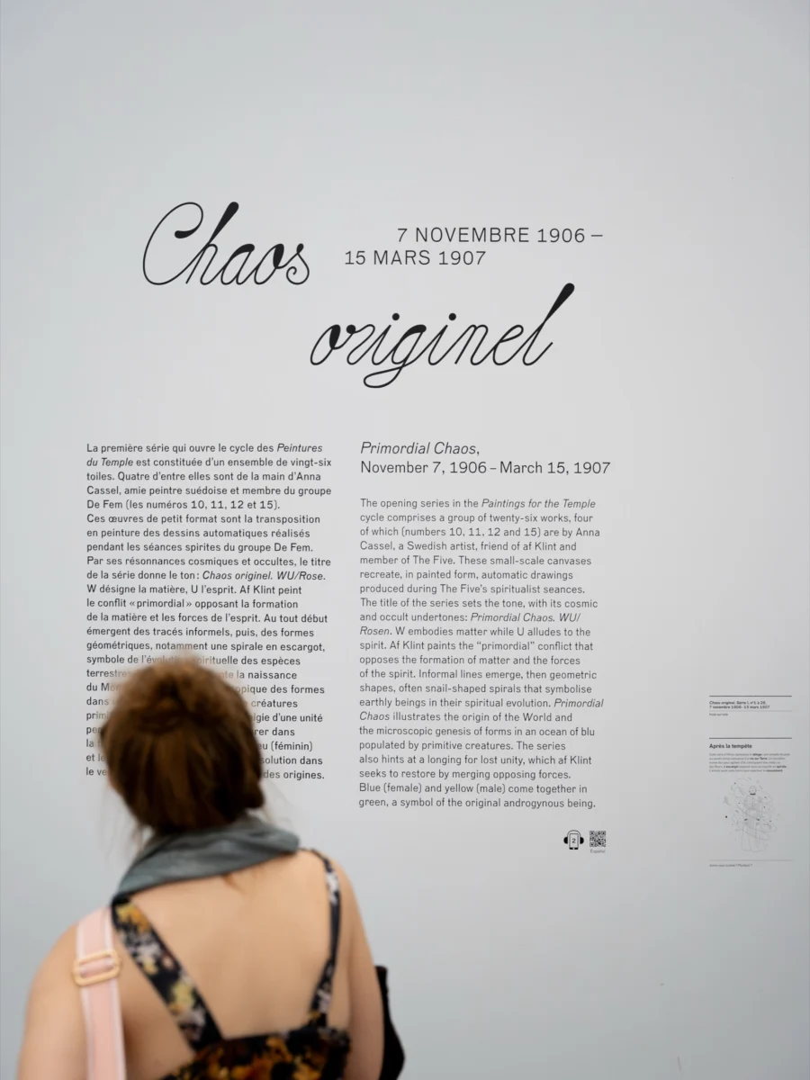 Reportage photo d'événement à Paris : panneau de texte explicatif d'une exposition, visiteuse de dos
