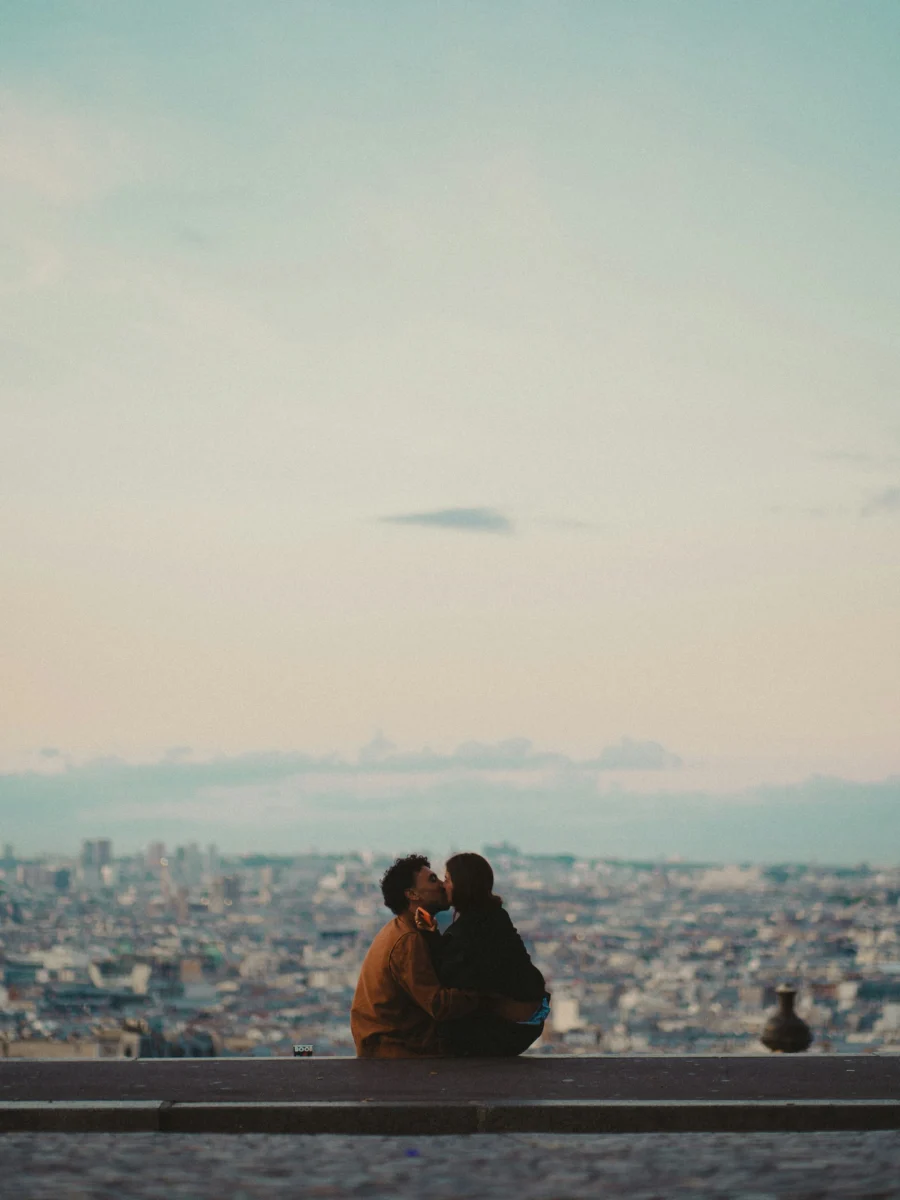 Un couple s’embrasse sur un parapet dominant la ville