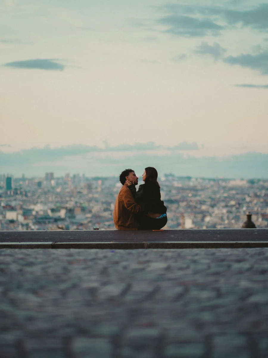 Un couple assis face aux toits de la ville