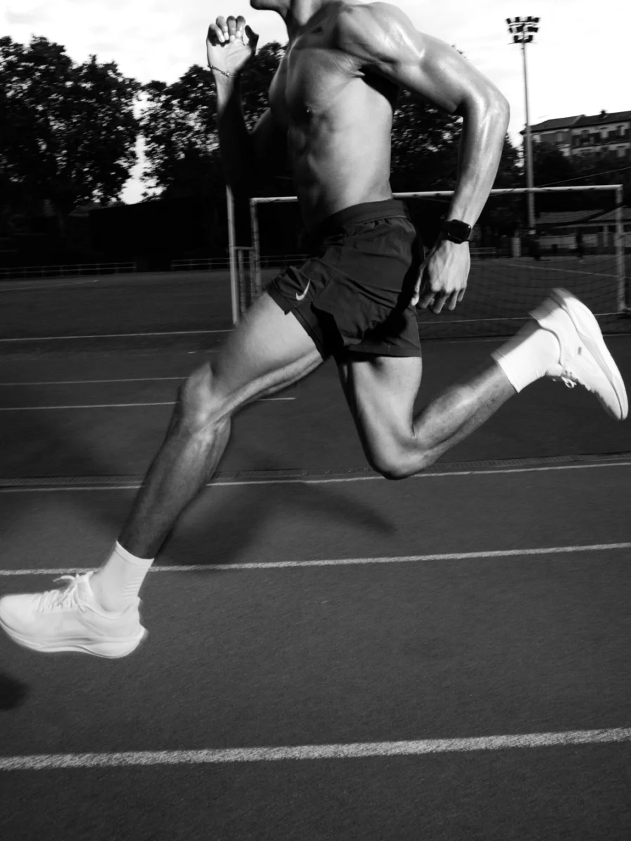 Coureur en pleine foulée sur une piste d'athlétisme, noir et blanc