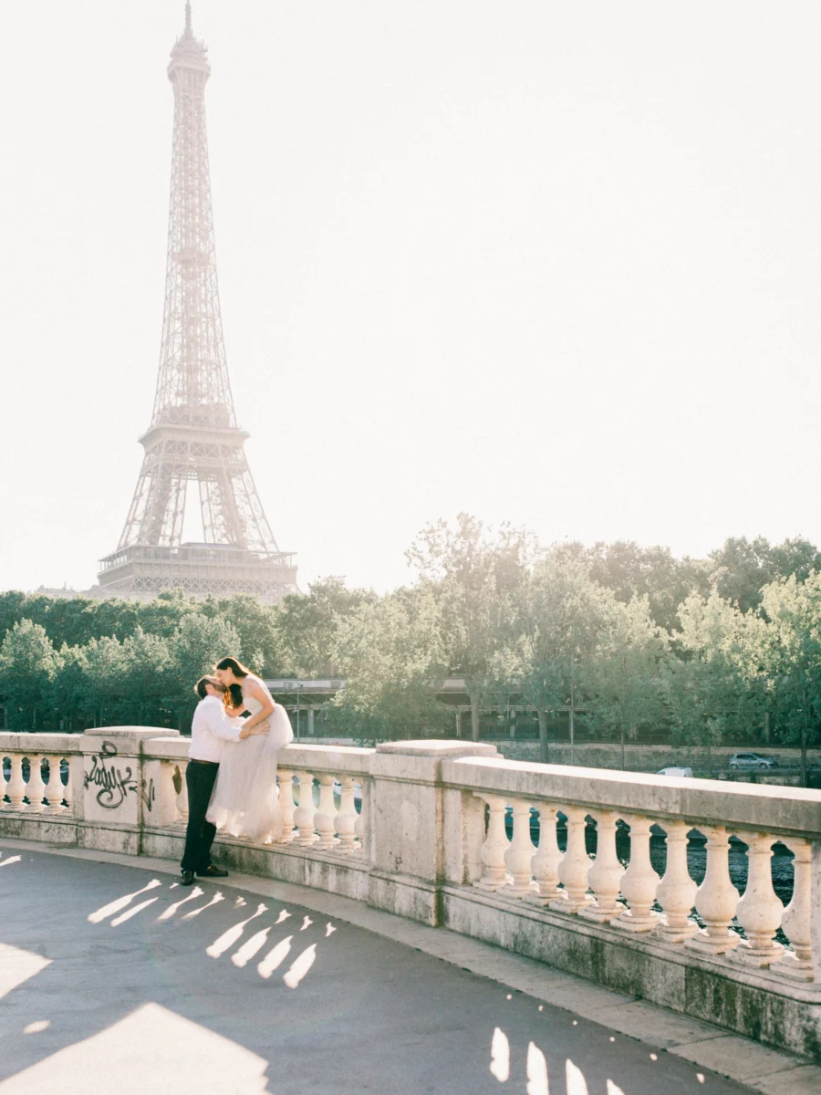 Couple s’embrassant sur un pont, tour Eiffel en arrière-plan