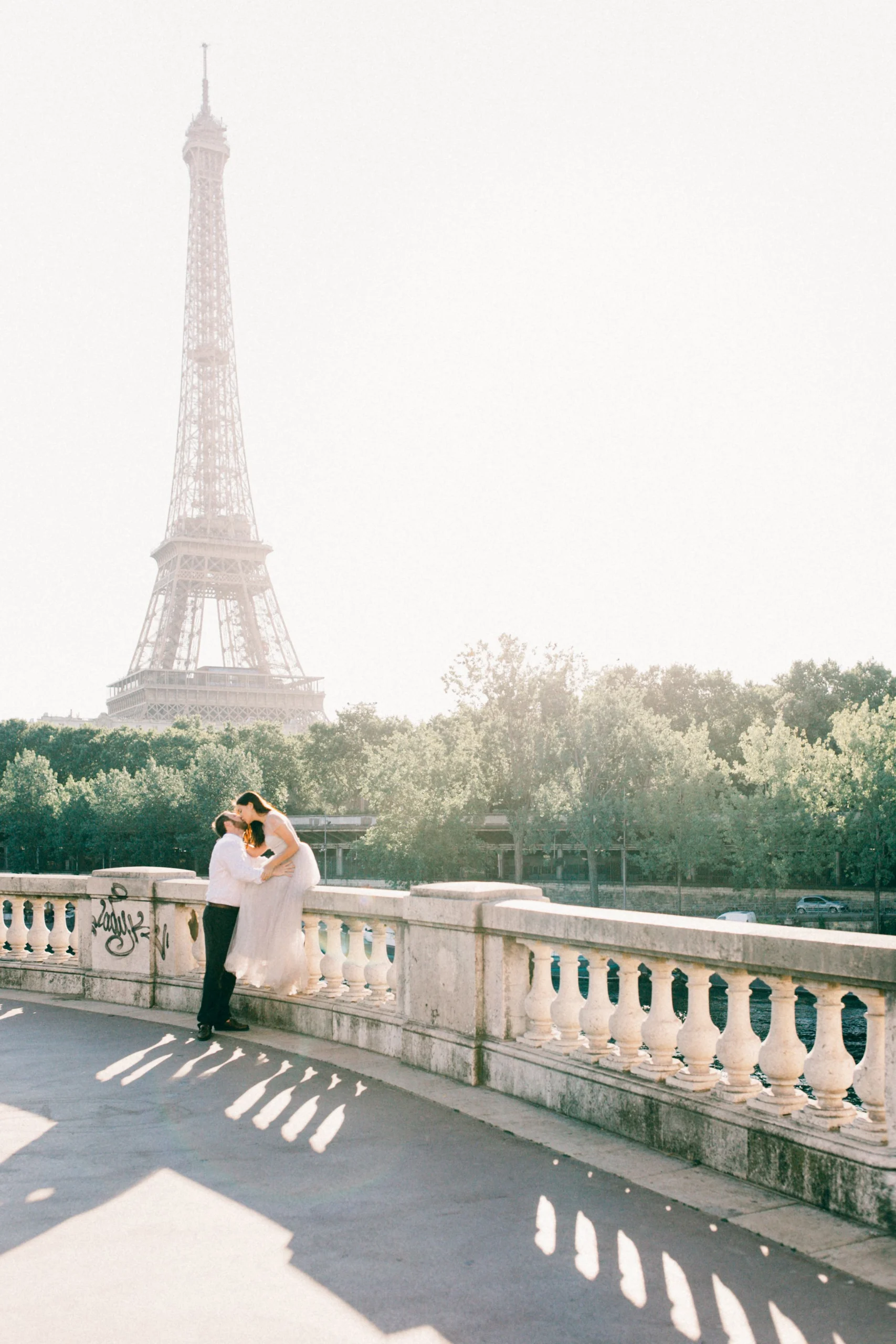 Couple s’embrassant sur un pont, tour Eiffel en arrière-plan