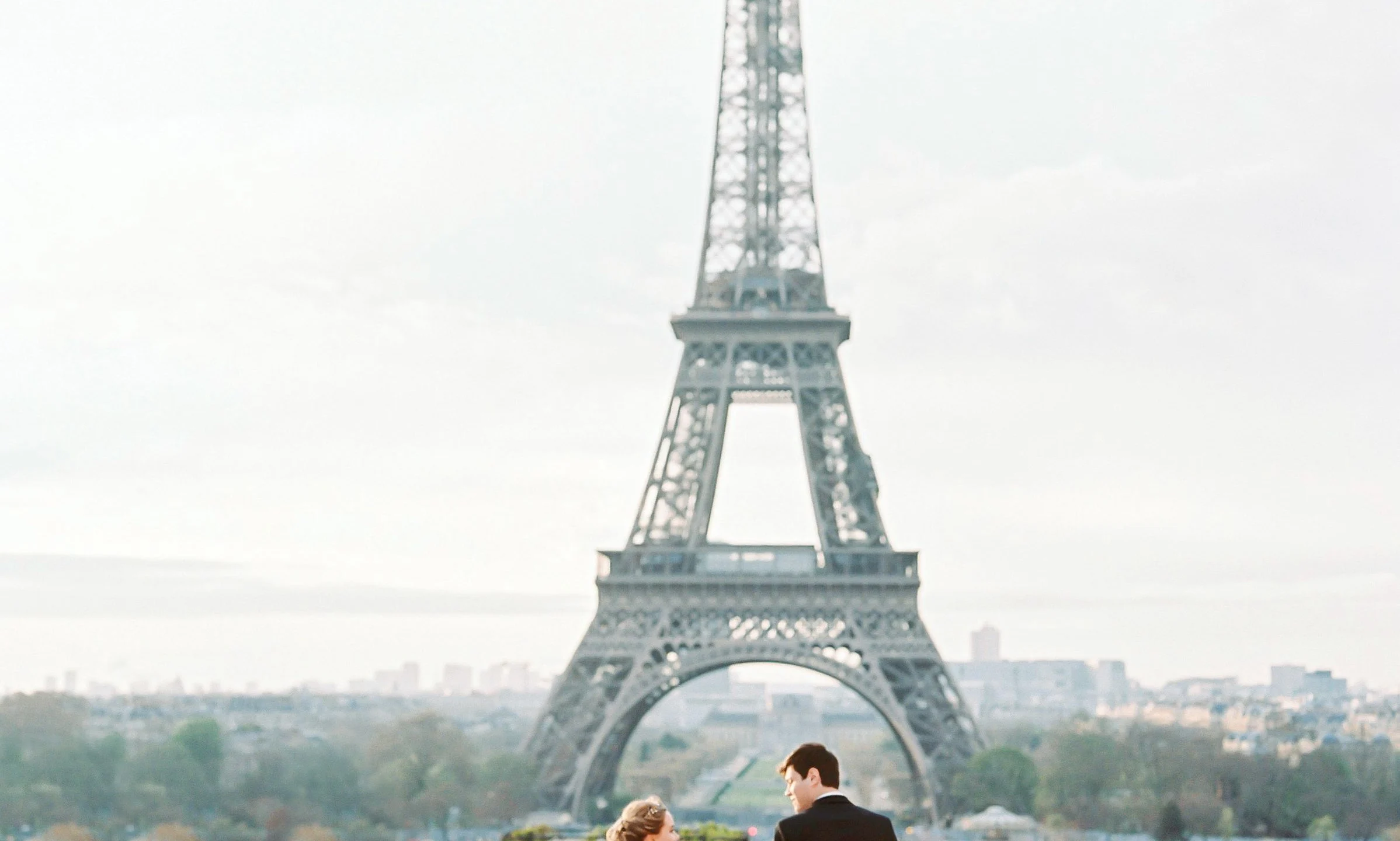 Jeunes mariés se tenant la main devant la tour Eiffel