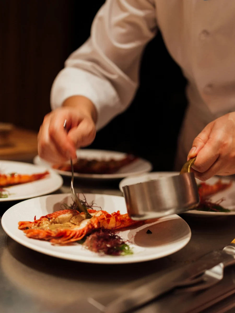 Un chef en veste blanche dresse une assiette