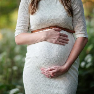 Une femme enceinte tient son ventre, lumière naturelle en extérieur