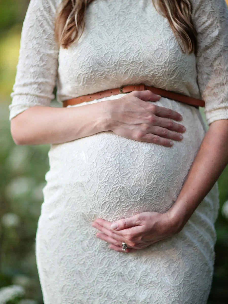 Une femme enceinte tient son ventre, lumière naturelle en extérieur