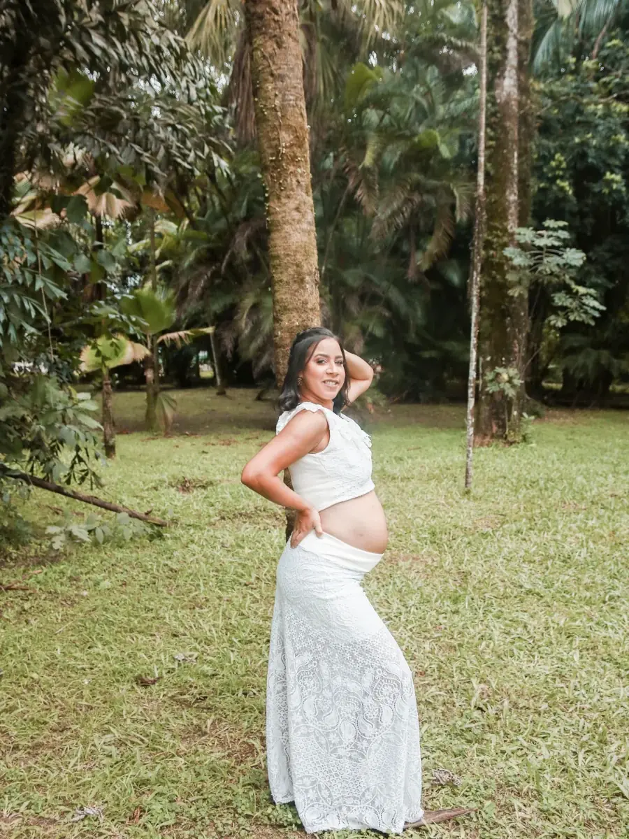 Femme enceinte souriante en extérieur, robe blanche