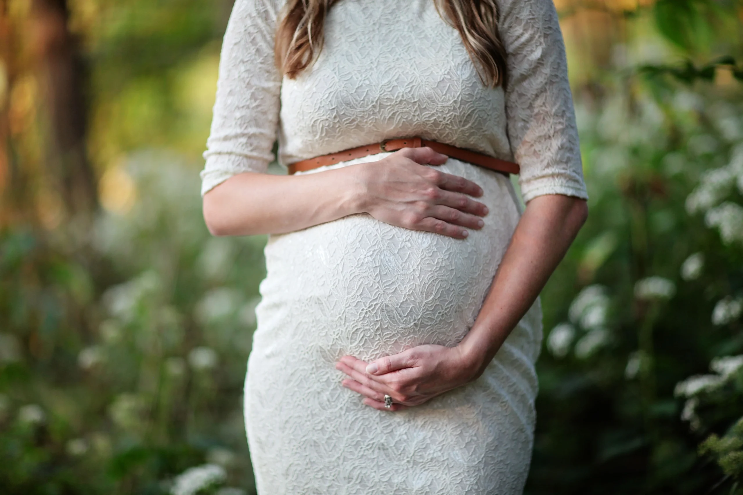 Une femme enceinte tient son ventre, lumière naturelle en extérieur