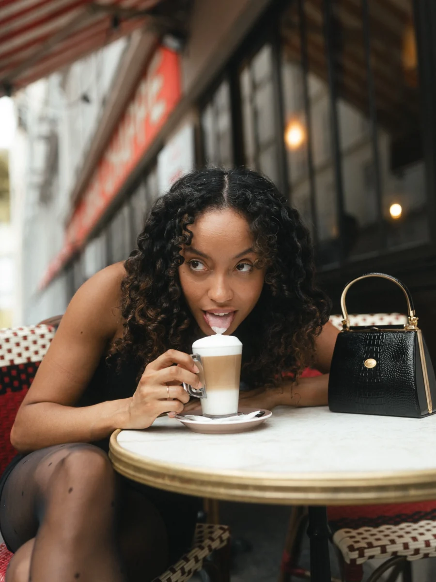 Jeune femme goûtant la mousse d'un café latte à la terrasse d'un café à Montmartre