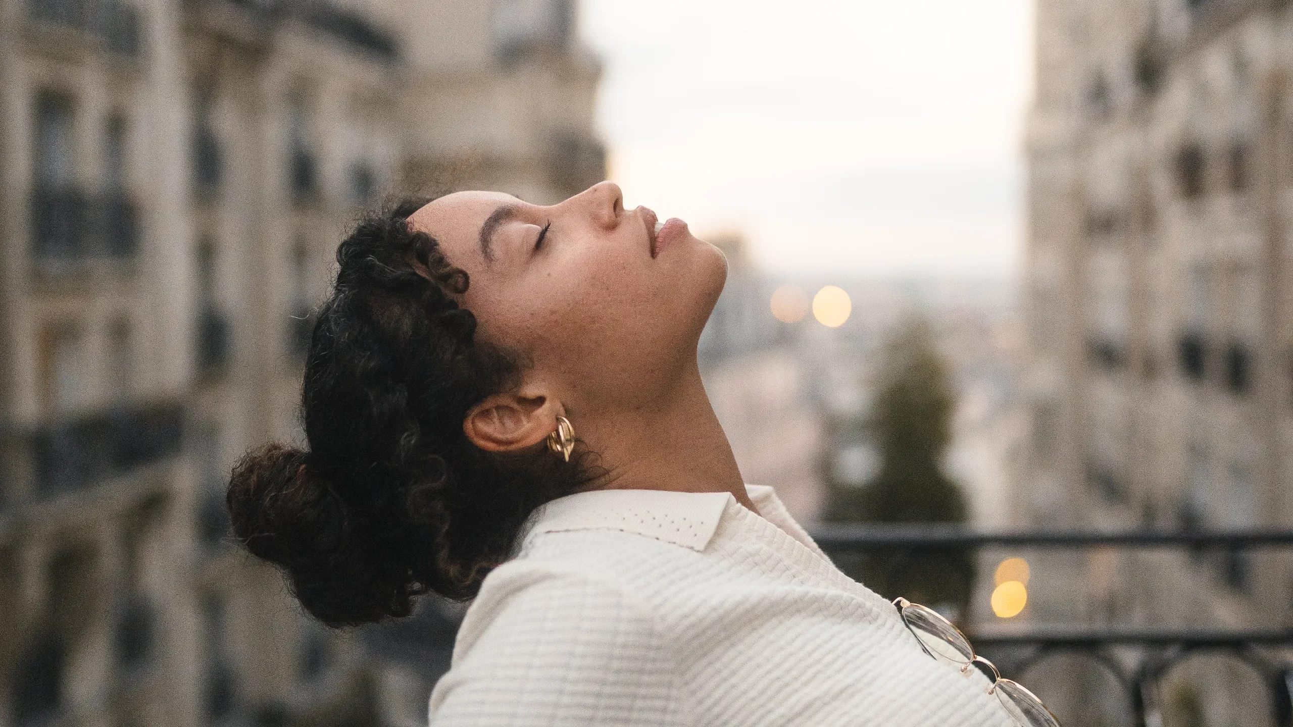 Portrait sur un balcon parisien, vue sur les toits au crépuscule