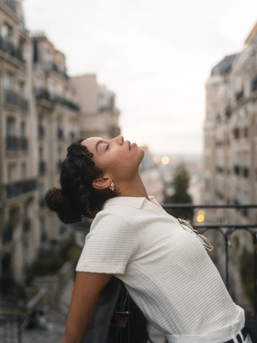 Portrait sur un balcon parisien, vue sur les toits au crépuscule