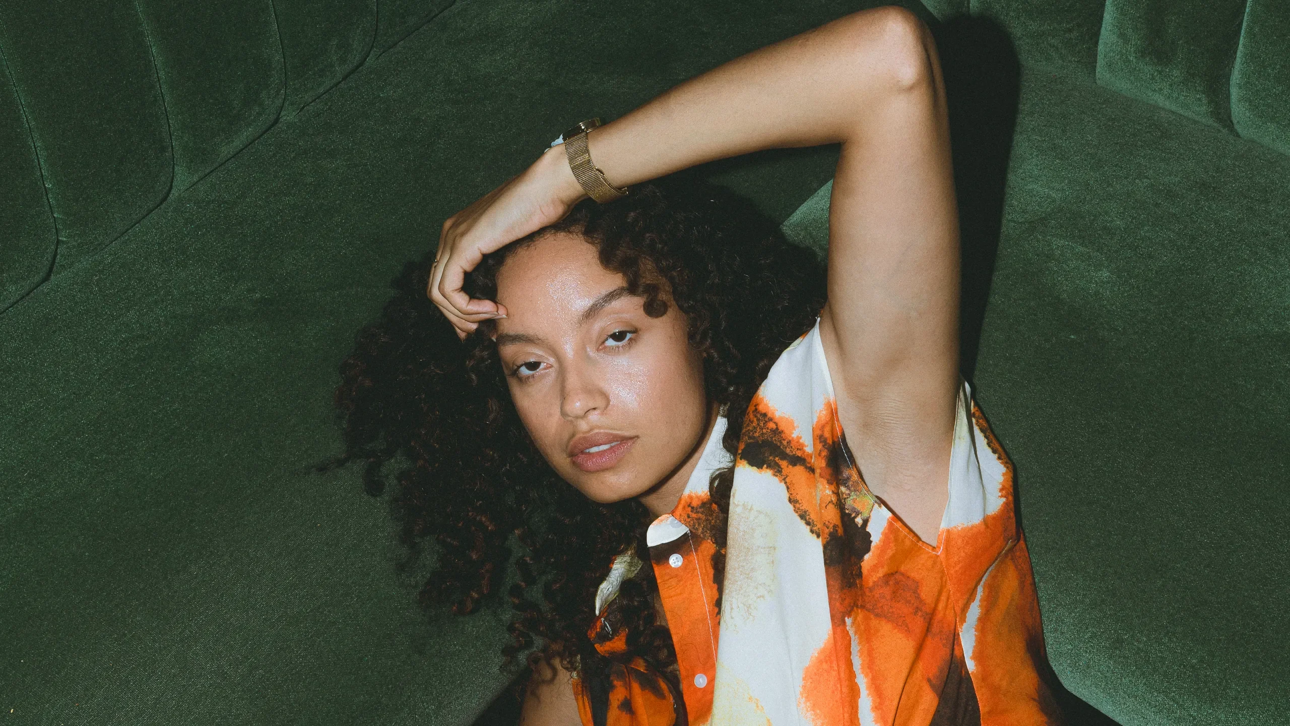 Portrait mode en tenue fleurie orange, banquette en velours vert