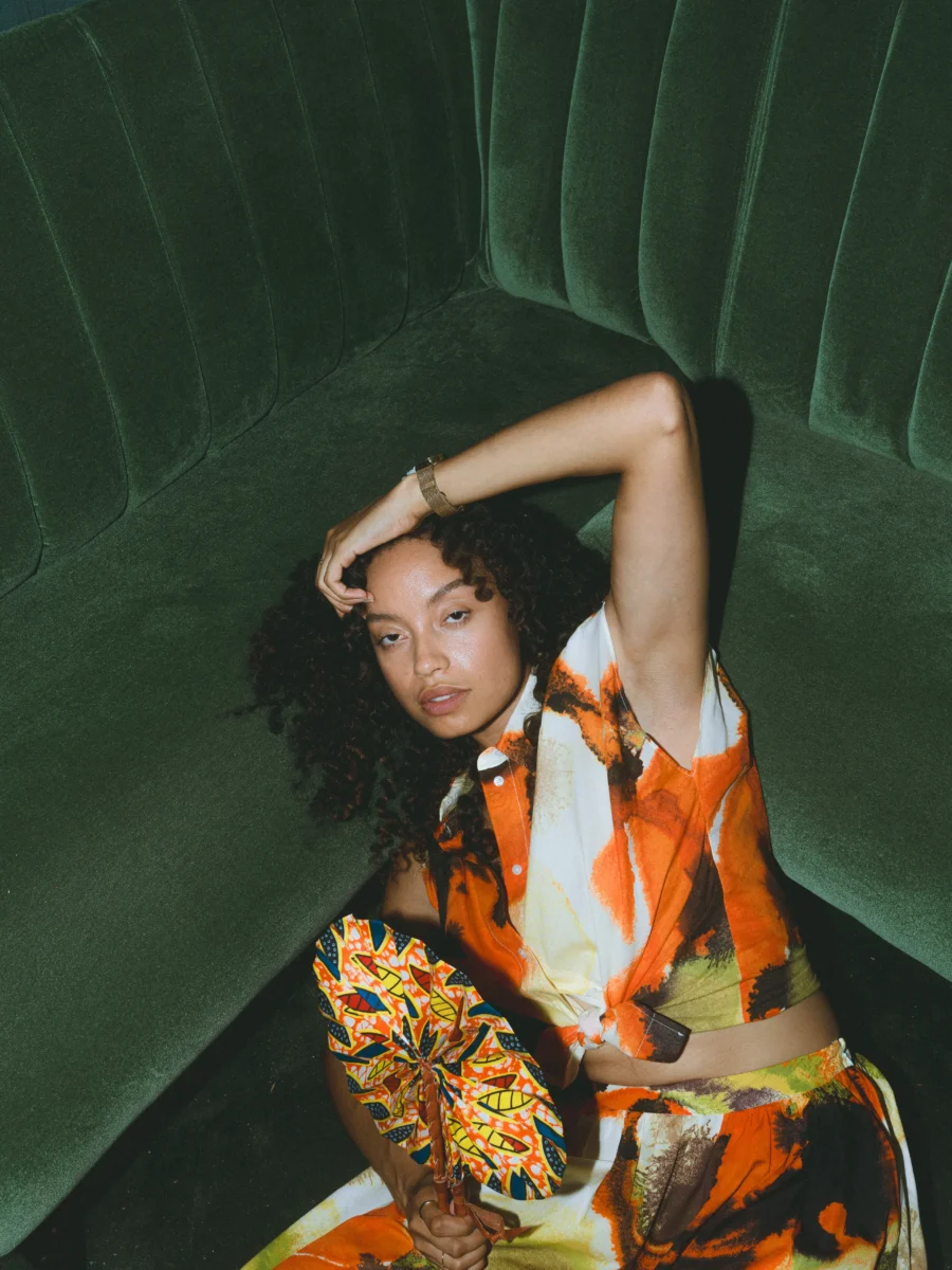 Portrait mode en tenue fleurie orange, banquette en velours vert