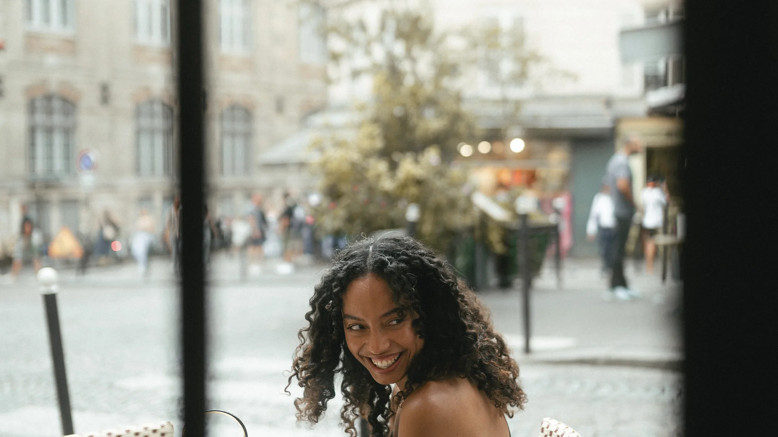 Portrait pris à travers la vitrine d'un café à Montmartre, place parisienne en arrière-plan