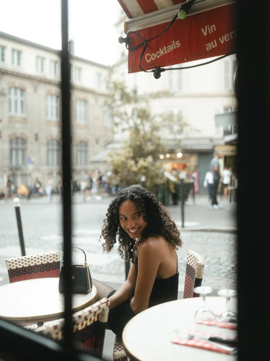 Portrait pris à travers la vitrine d'un café à Montmartre, place parisienne en arrière-plan