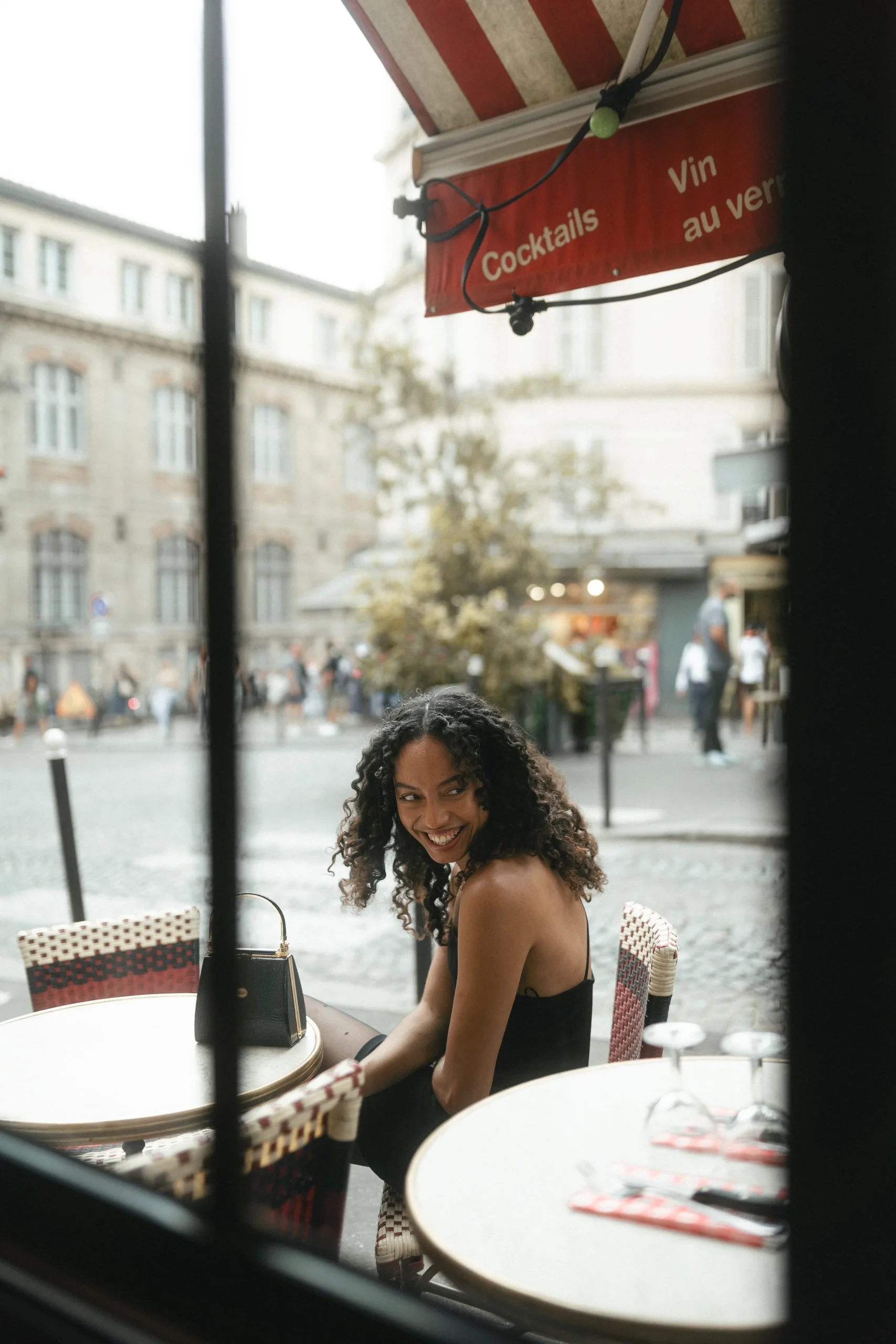 Portrait pris à travers la vitrine d'un café à Montmartre, place parisienne en arrière-plan