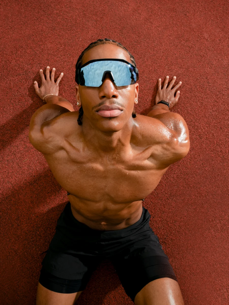 Portrait sportif torse nu avec lunettes de soleil, fond rouge