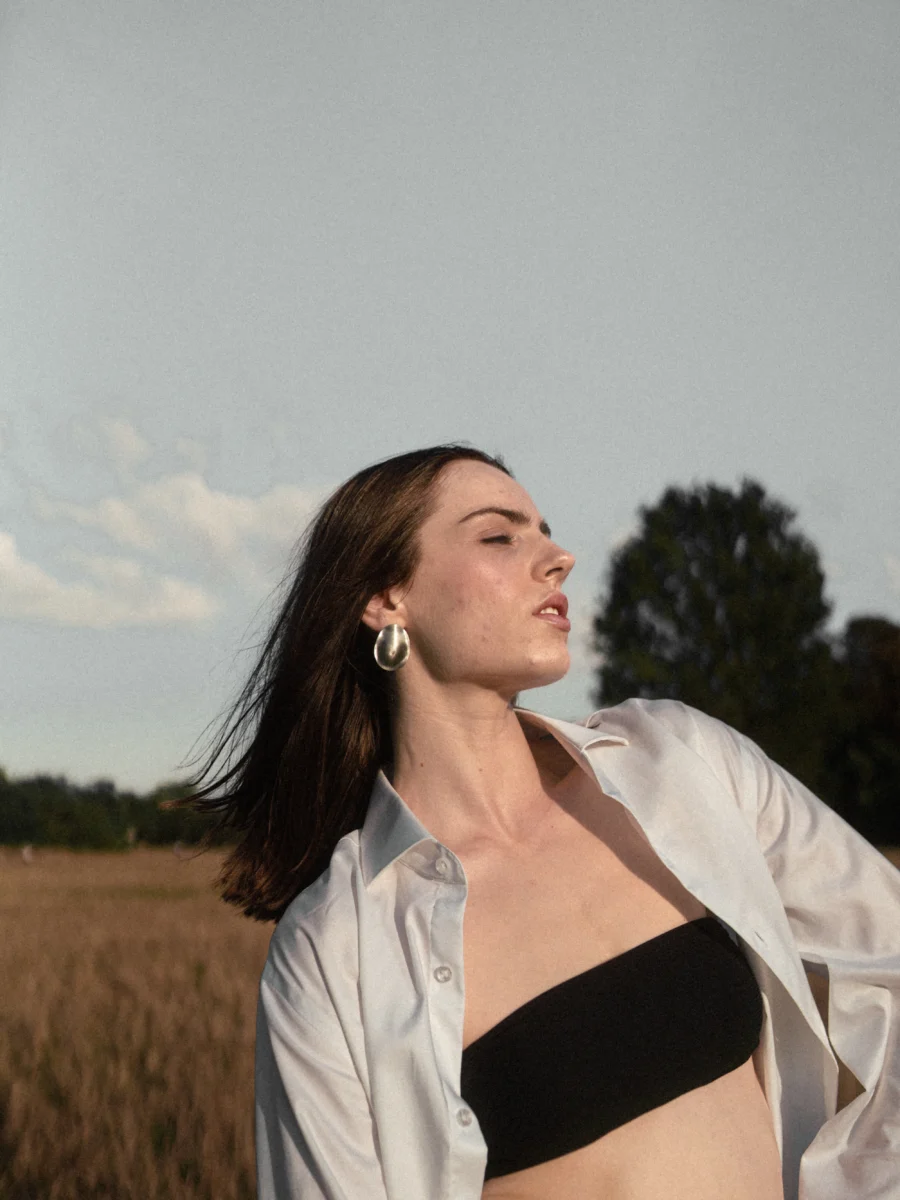 Portrait with eyes closed, wind in her hair, a field behind