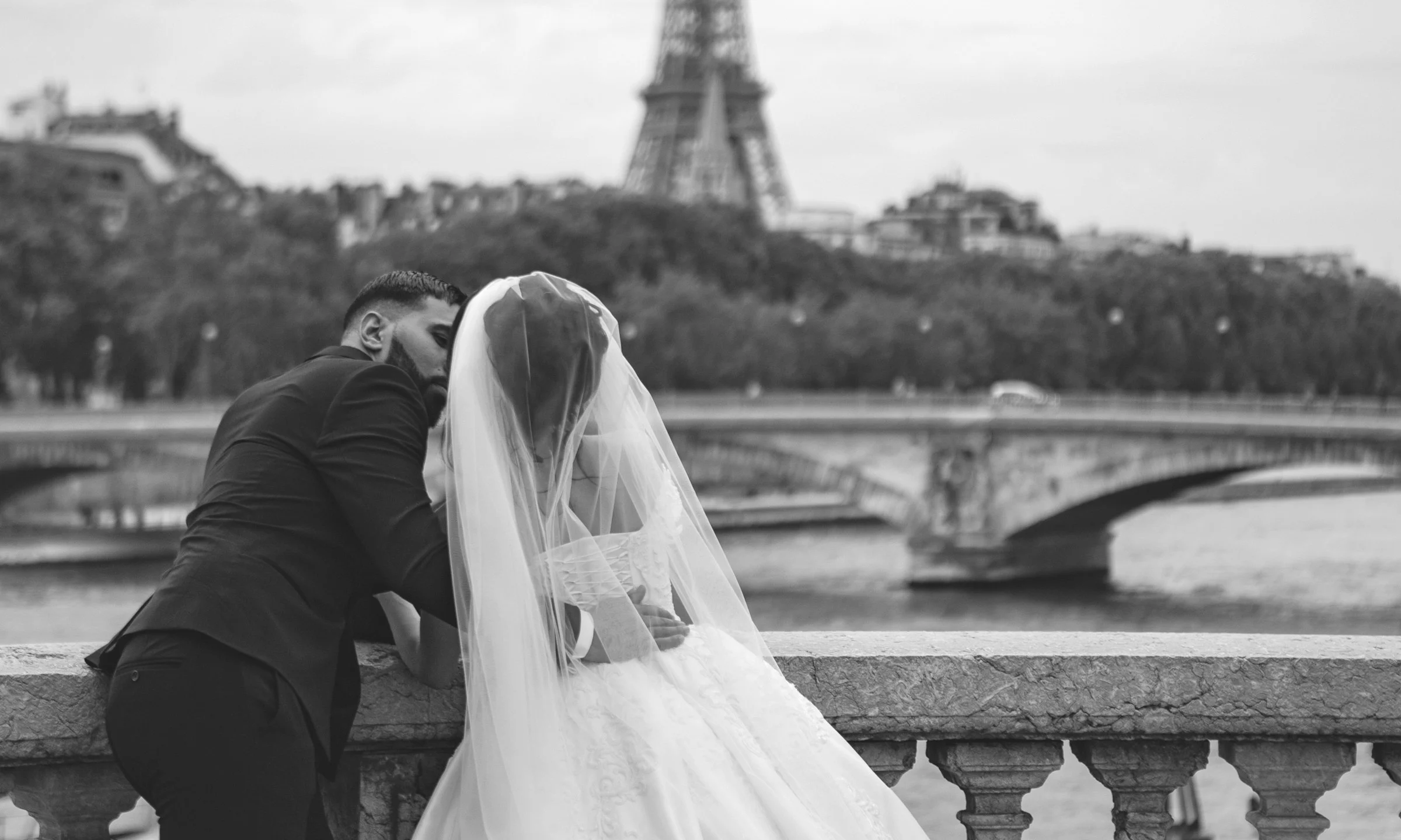 Photographie en noir et blanc d’un couple devant la tour Eiffel