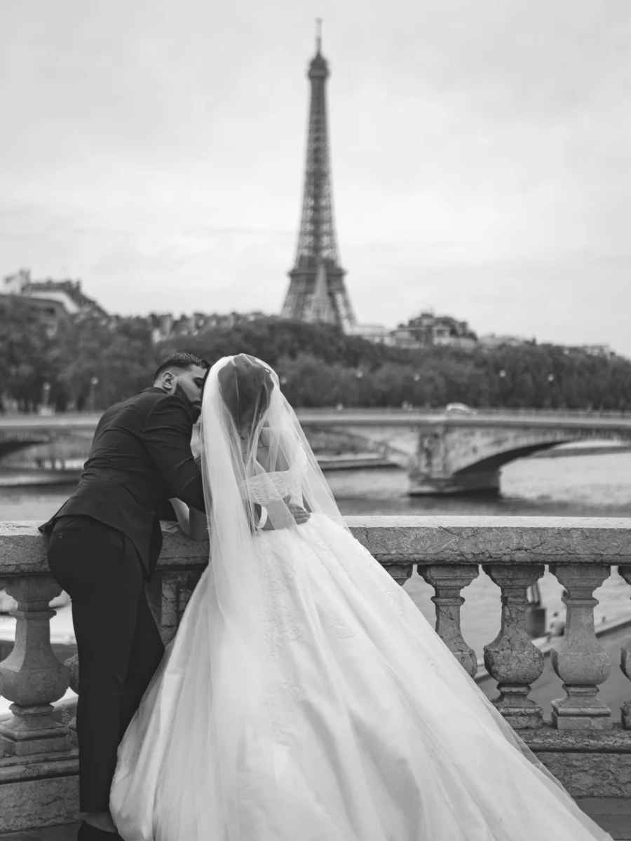 Photographie en noir et blanc d’un couple devant la tour Eiffel