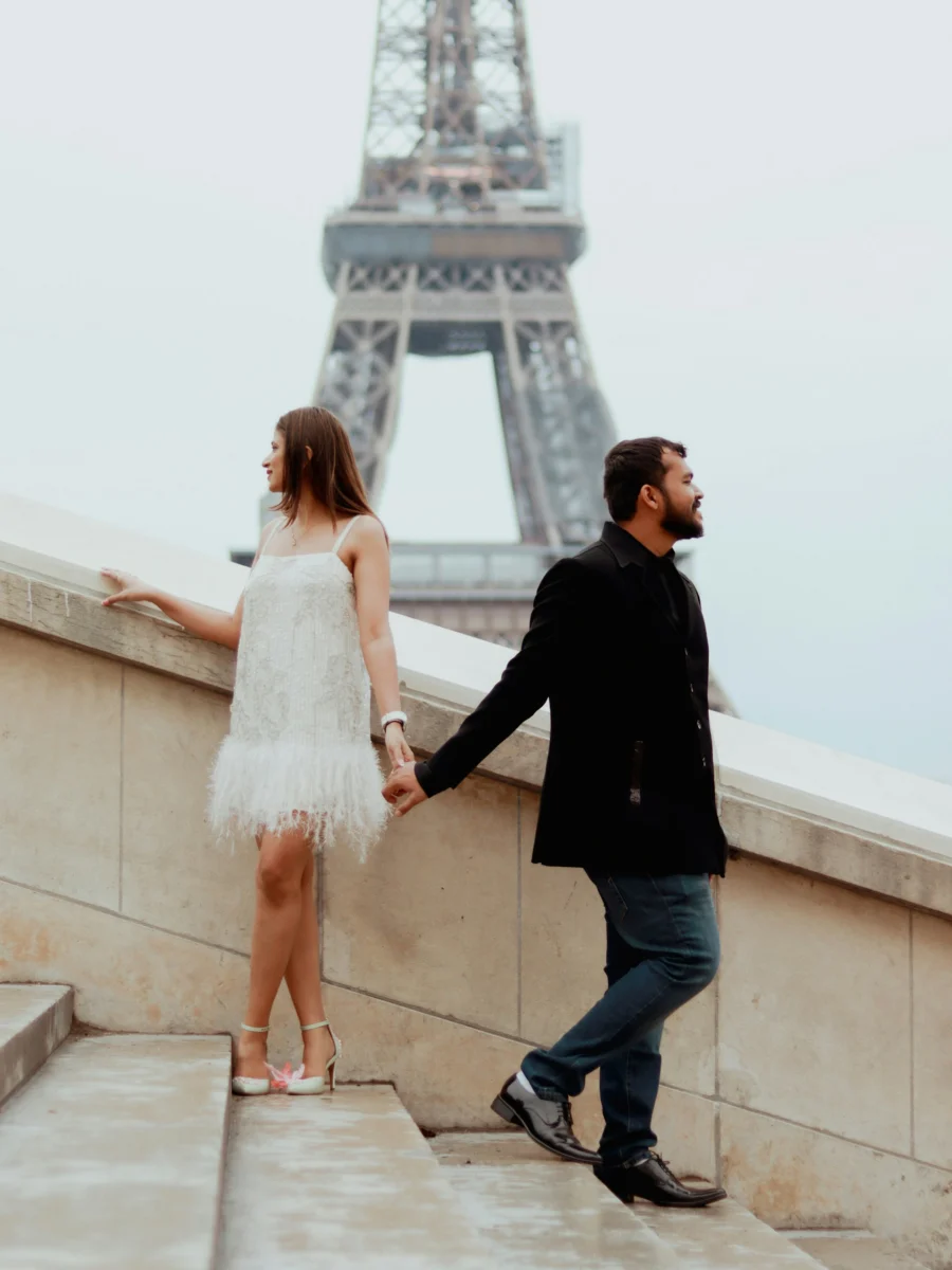Un couple se tient la main près de la tour Eiffel