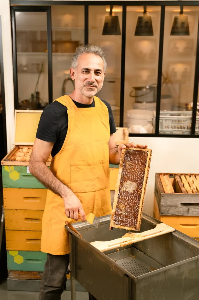 Volkan Tanaci tient un cadre de miel devant l’extracteur, dans l’atelier CityBzz
