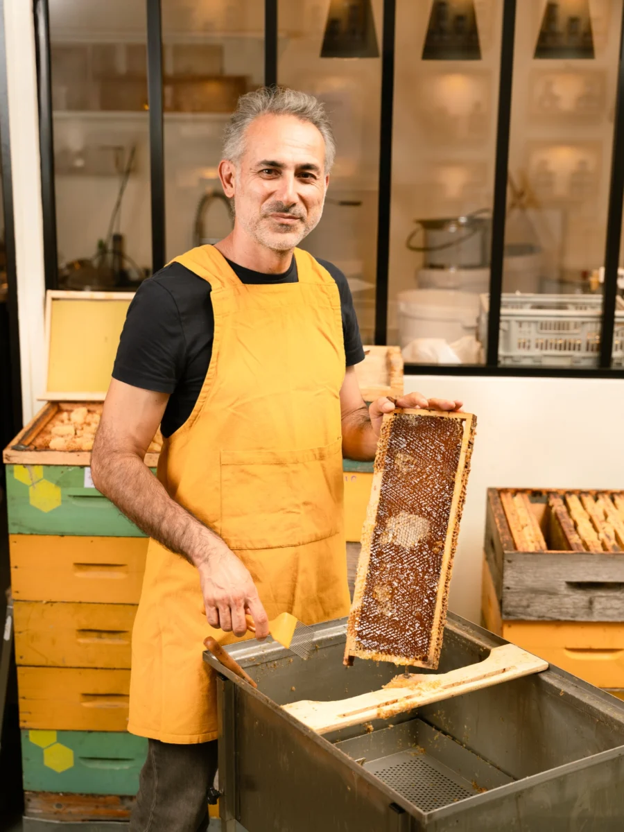 Volkan Tanaci, fondateur de CityBzz, tient un cadre de miel devant l’extracteur dans son atelier à Paris