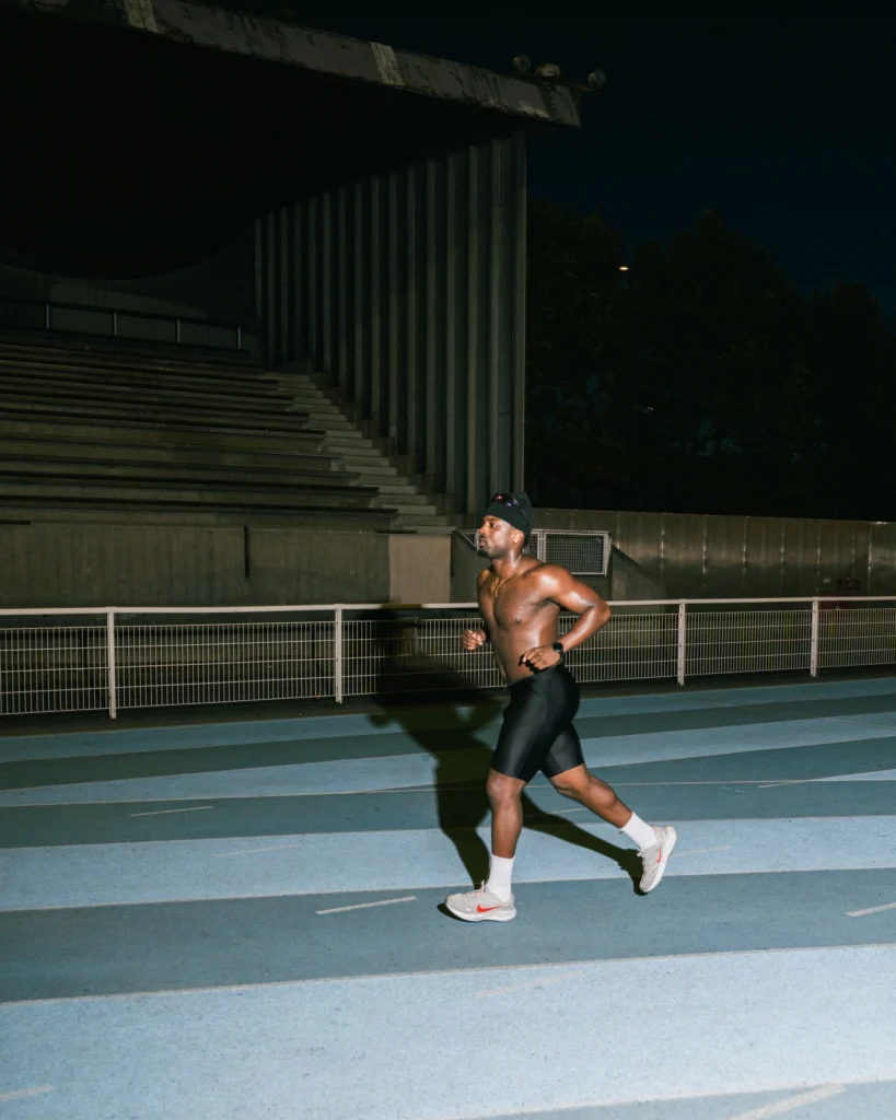 Coureur seul sur la piste, de nuit, devant les gradins