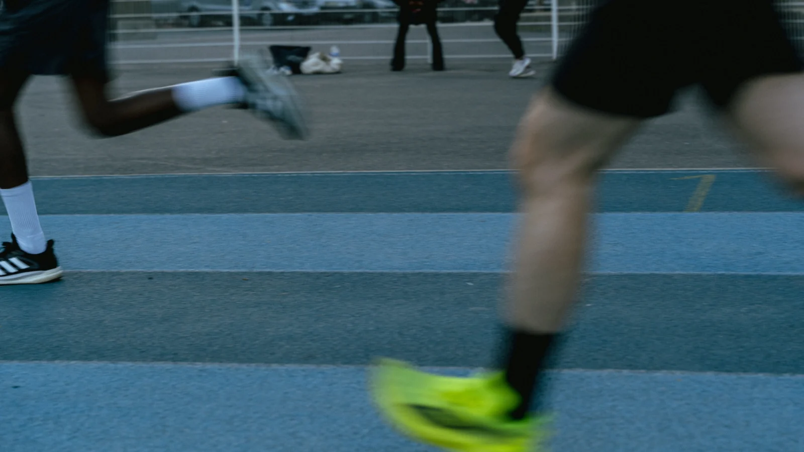 Jambes de deux coureurs en mouvement sur une piste bleue
